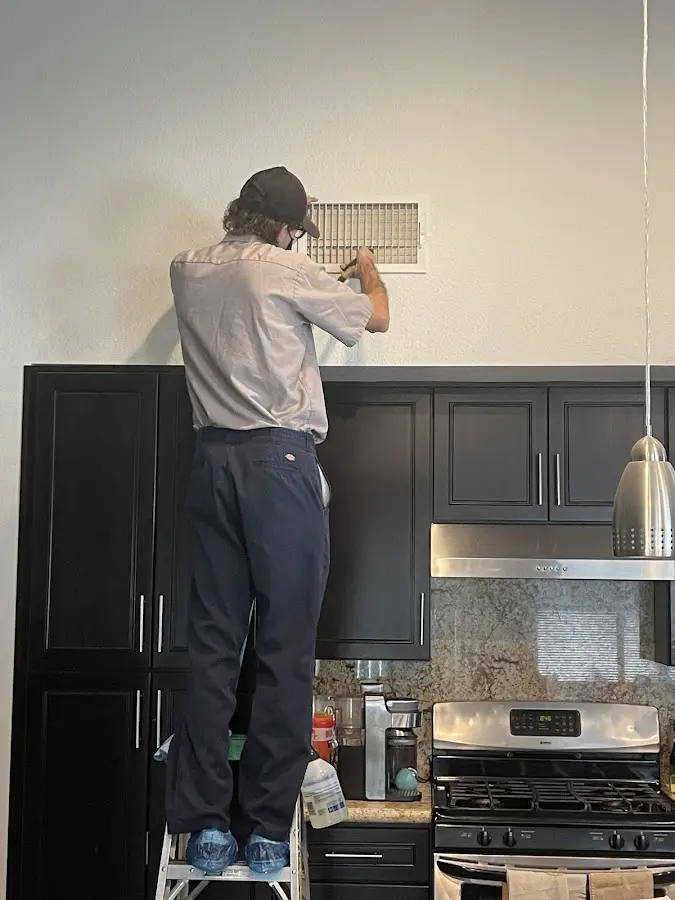 Technician inspecting an air vent during HVAC service in Jefferson